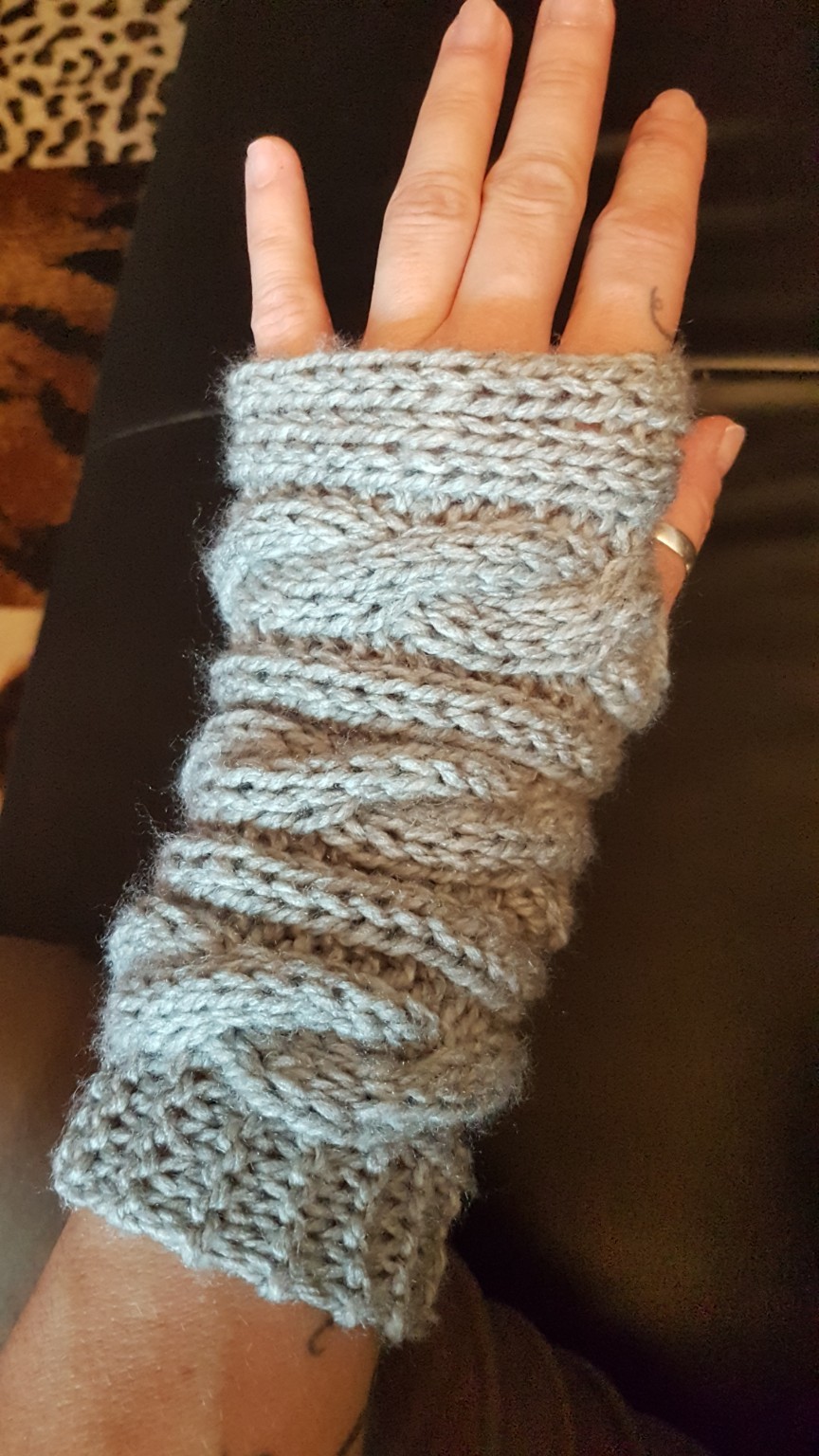 Grauer gestrickter Pulswärmer mit verschiedenen Strickmustern